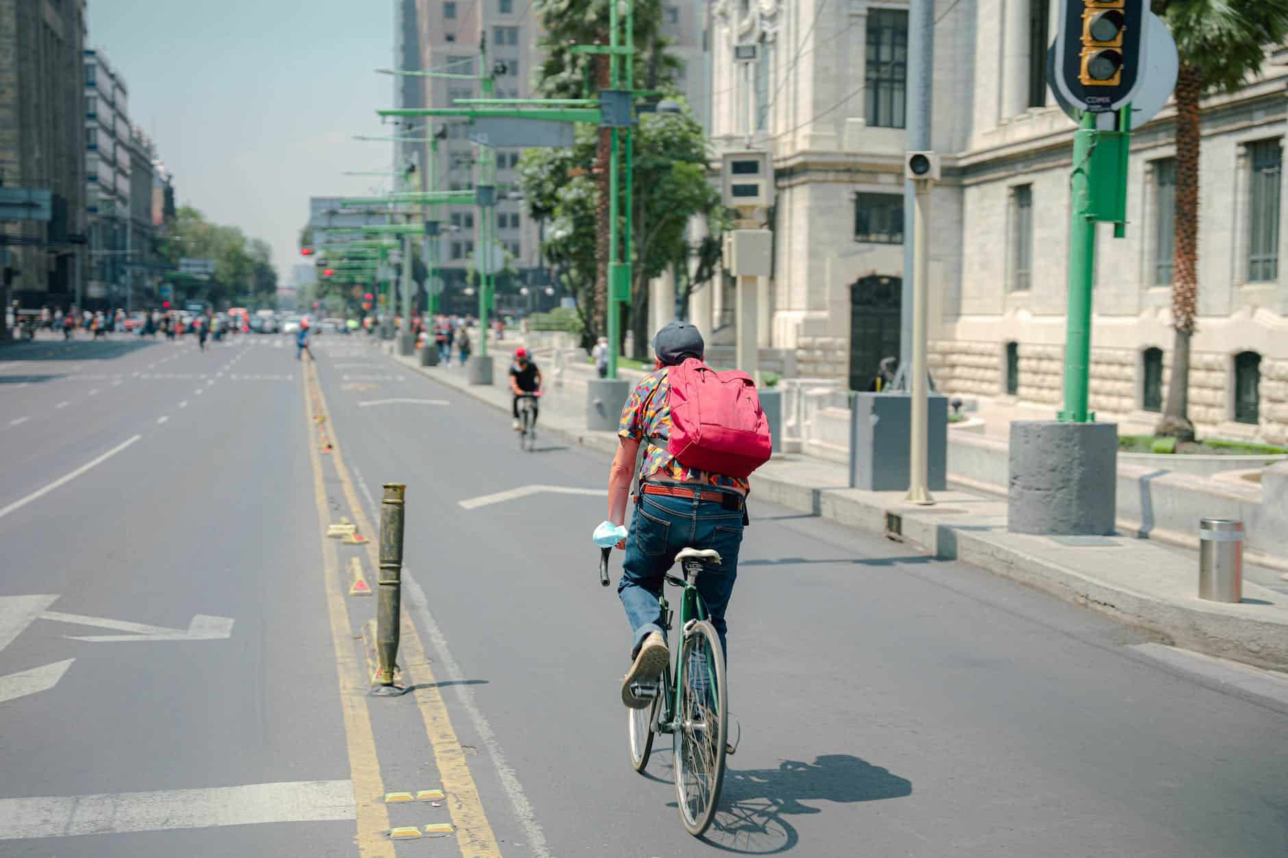 man in colorful shirt riding bicycle on road