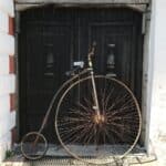 old penny farthing parked on street pavement in sunlight