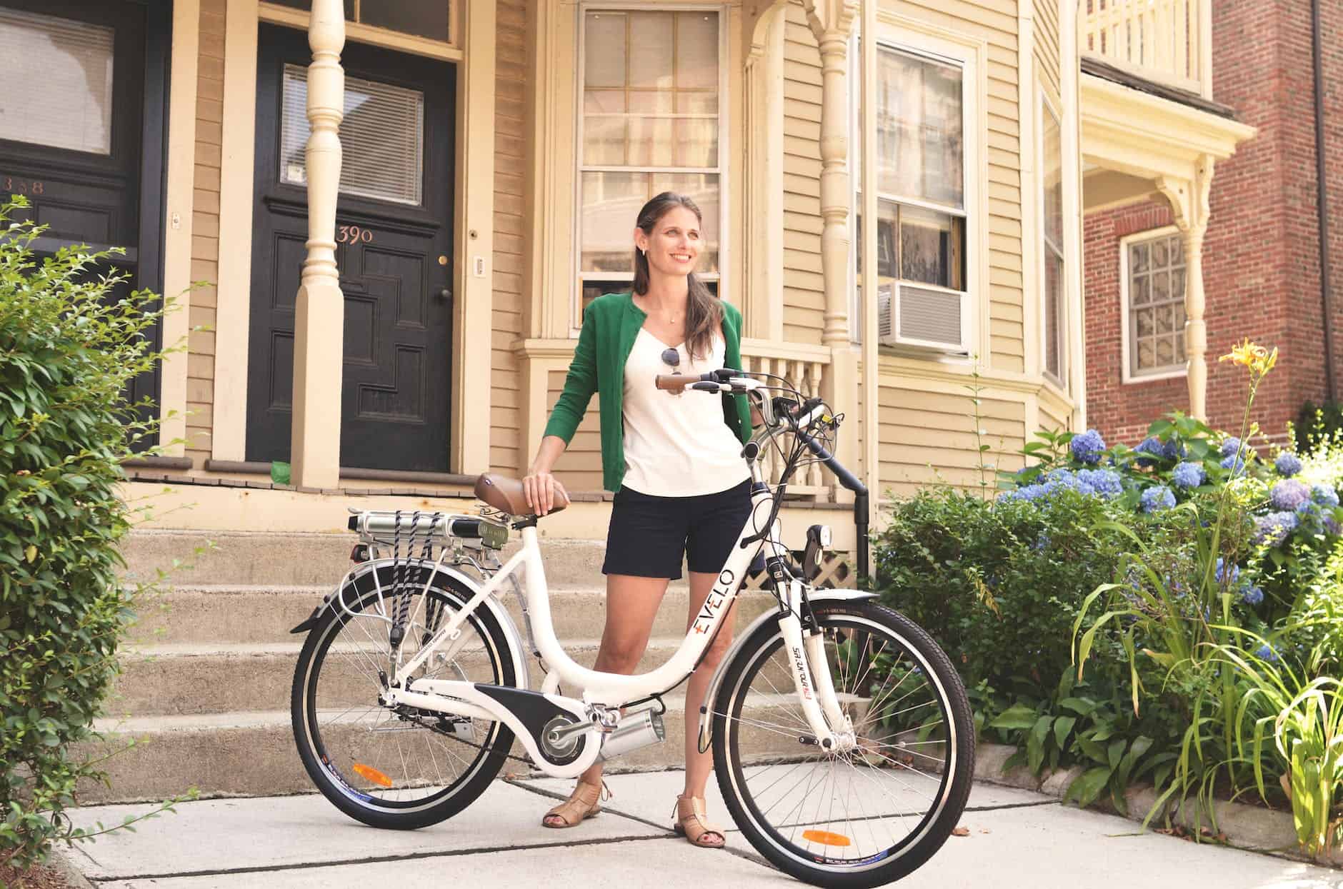 a woman in a green cardigan holding an electric bike