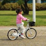 girl in pink jacket riding bicycle during daytime