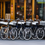 An image showcasing a bustling city street with a variety of bike shops, their windows filled with vibrant displays of sleek electric bikes, attracting customers eager to explore the USA on these eco-friendly rides